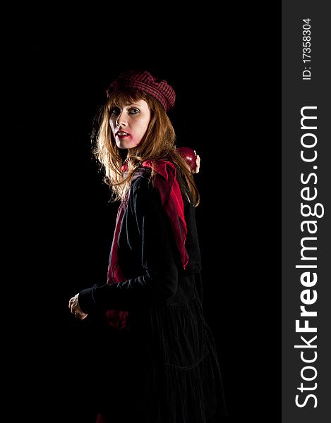 Girl with red socks hat scarf and apple on black background