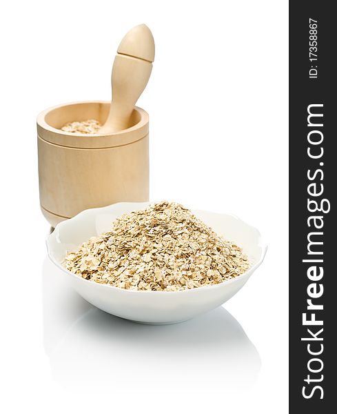 Cereal in bowl and in wooden mortar with pestle isolated on white background with reflection on white blurry background. Cereal in bowl and in wooden mortar with pestle isolated on white background with reflection on white blurry background