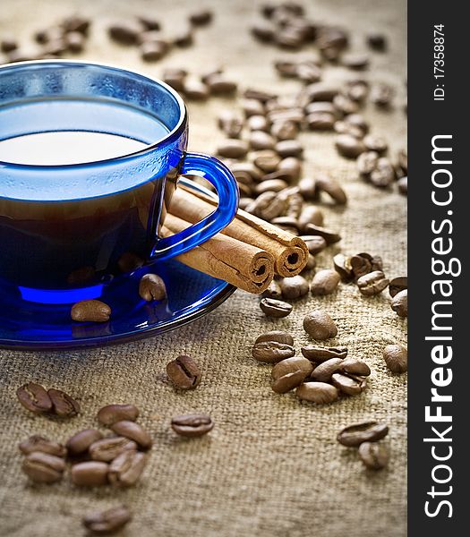Cinnamon and coffee beans with cup on saucer