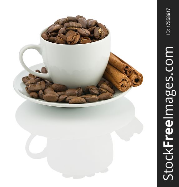 Cup with coffee beans and cinnamon sticks isolated on white background with reflection on white blurry background