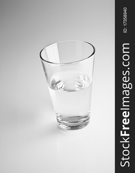 One glass with water on a blurry gray background. One glass with water on a blurry gray background