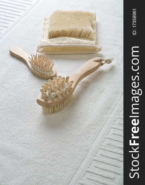 Wooden hairbrush massager and bast on white cotton towel