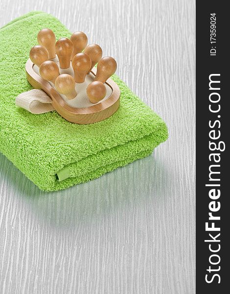 Brown wooden massager on green cotton towel and all its on a abstract gray background. Brown wooden massager on green cotton towel and all its on a abstract gray background