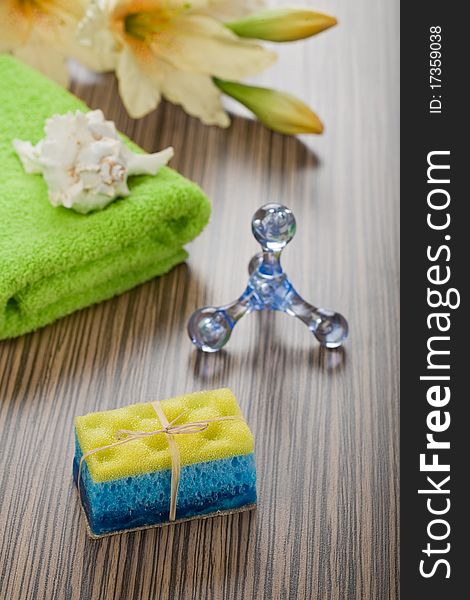 Objects for bathing plastical blue massager green cotton towel hanmade soap combination with yellow sponge flower and cockle shell all its on wooden background. Objects for bathing plastical blue massager green cotton towel hanmade soap combination with yellow sponge flower and cockle shell all its on wooden background