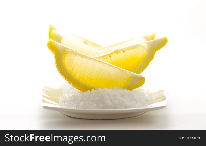 Sliced sour lemons on a bed of sweet coarse sugar, isolated on white background.