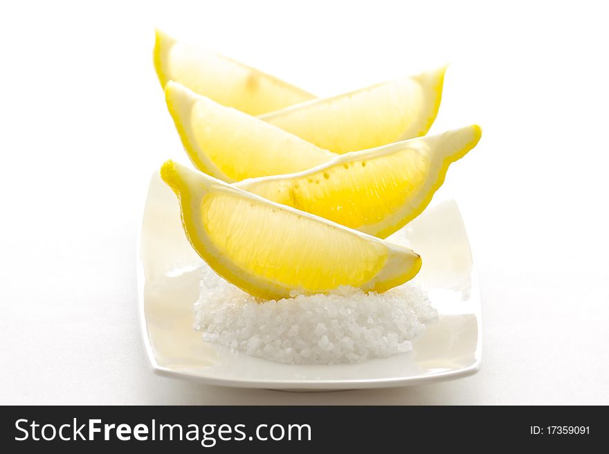 Sliced sour lemons on a bed of sweet coarse sugar, isolated on white background.