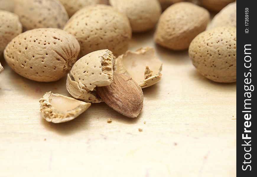 Some almonds on a table, shelled and one unshelled