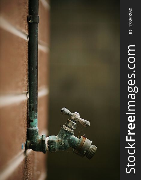 Old water valve tap on briÑk wall