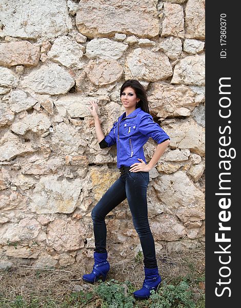 Attractive young girl standing near the old stone wall. Attractive young girl standing near the old stone wall