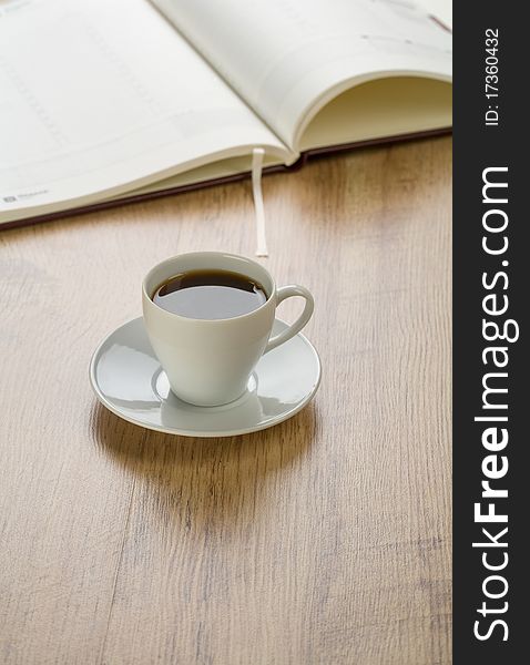 Diary with cup of coffee on wooden background