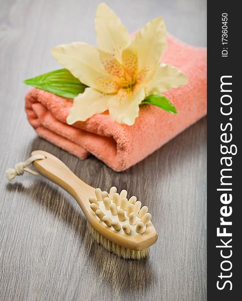 Flower on pink towel with massager and brush on wooden background