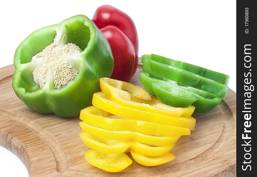 Colorful bell peppers, cut into slices on a wooden board