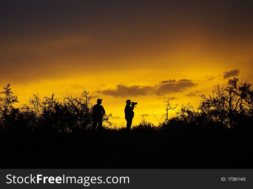 Silhouettes of two people at the sunset