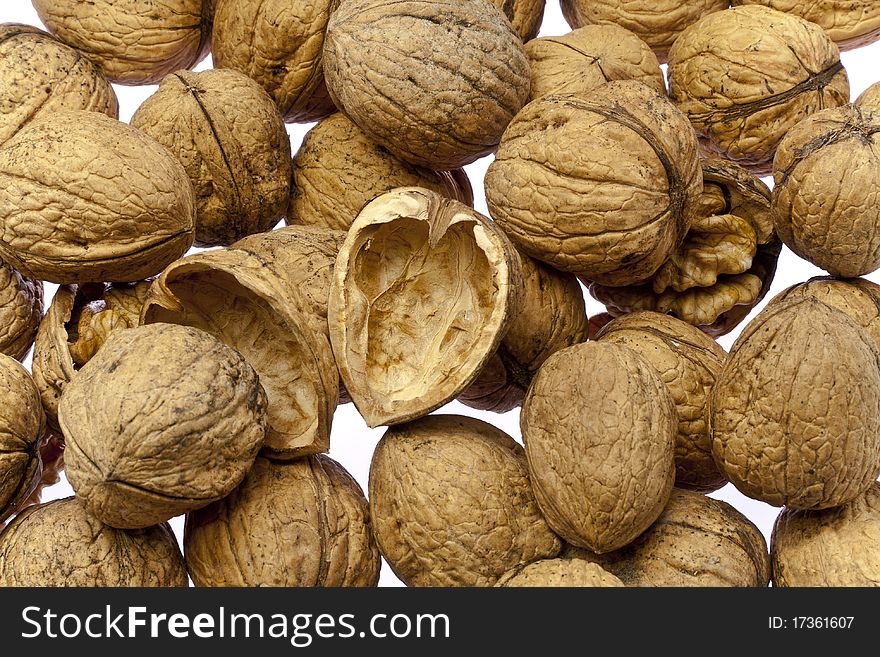 Whole walnuts and cracked walnuts as background texture but on a white surface