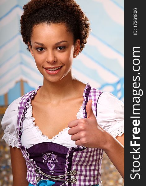 Beautiful dark skinned girl standing in a beer tent wearing a traditional dirndl. Beautiful dark skinned girl standing in a beer tent wearing a traditional dirndl