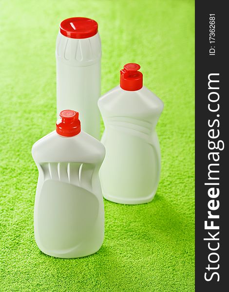 Three white plastical kitchen cleaners with red lids on green cotton towel. Three white plastical kitchen cleaners with red lids on green cotton towel