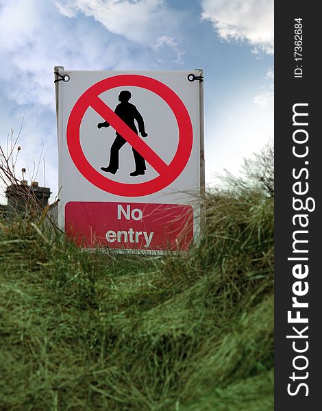No entry sign on grass with clouds
