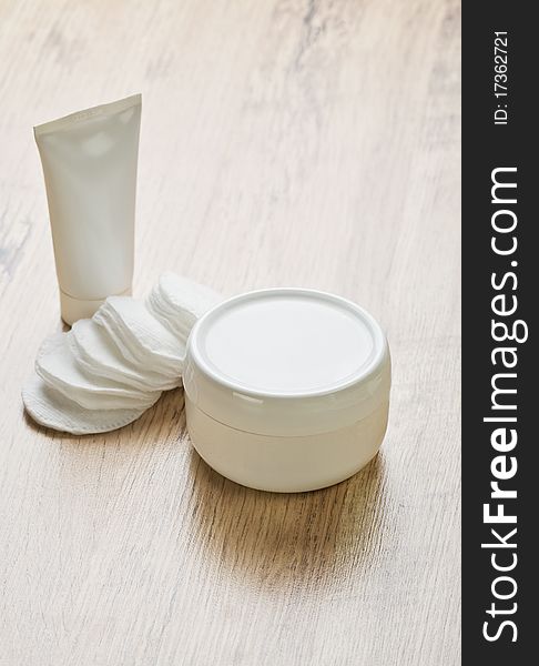 White tube jar of cream and cotton pads on wooden background. White tube jar of cream and cotton pads on wooden background