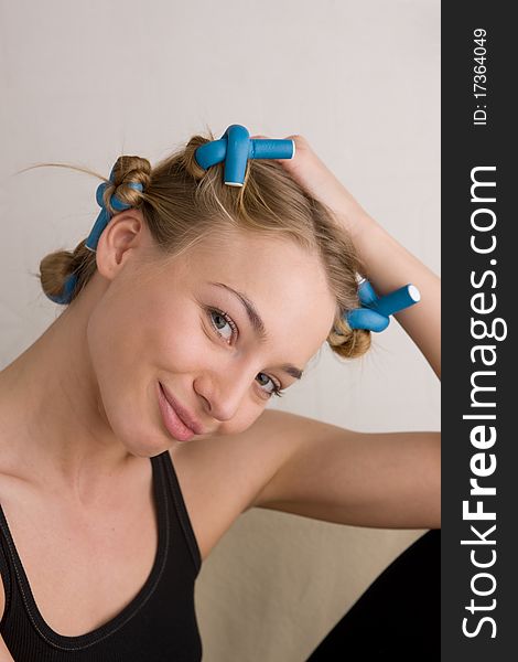 Beautiful young woman curls her hair with curlers. Beautiful young woman curls her hair with curlers.