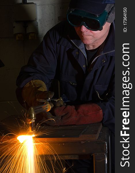 Welder uses torch to make sparks during removal of weld from metal equipment. Welder uses torch to make sparks during removal of weld from metal equipment.