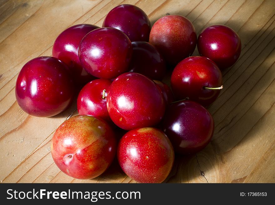 Organic red cherries and cherry plums on a wooden table