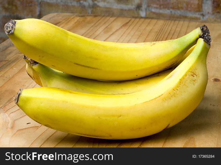 Bunch of rripe yellow bananas on a wooden table surface. Bunch of rripe yellow bananas on a wooden table surface