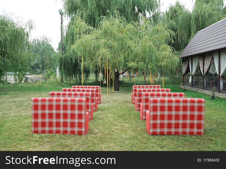 Rows of red empty chairs on a lawn before a wedding or ceremony