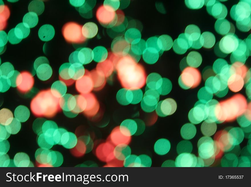 Abstract blur of green lights with a scattering of pinkish peach against a black background. Abstract blur of green lights with a scattering of pinkish peach against a black background.