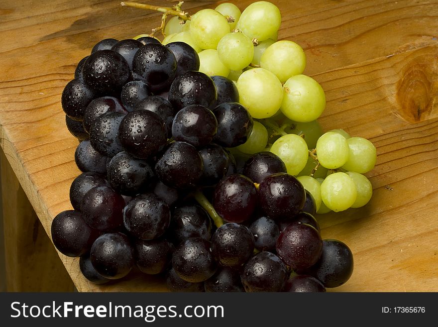 Fresh red and white organic grapes on a wooden table. Fresh red and white organic grapes on a wooden table