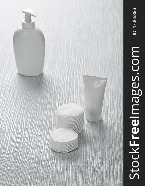Composition of white skincare items on the abstract gray background spray bottle one tube stack of cotton pads. Composition of white skincare items on the abstract gray background spray bottle one tube stack of cotton pads