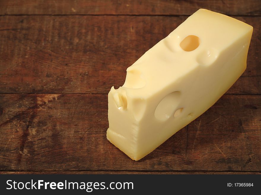 A piece of cheese lying on wooden background with copy space