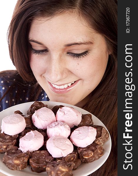 A woman with a plate full of candy and chocolate treats smelling them with a big smile on her face. A woman with a plate full of candy and chocolate treats smelling them with a big smile on her face.