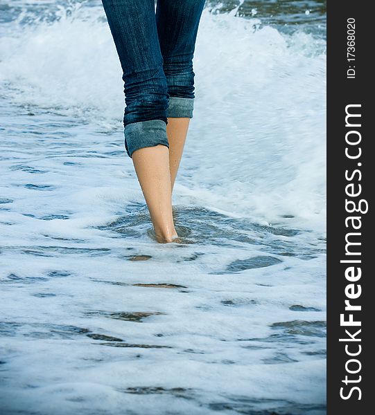 Legs of a young woman walking along the seacoast. Legs of a young woman walking along the seacoast