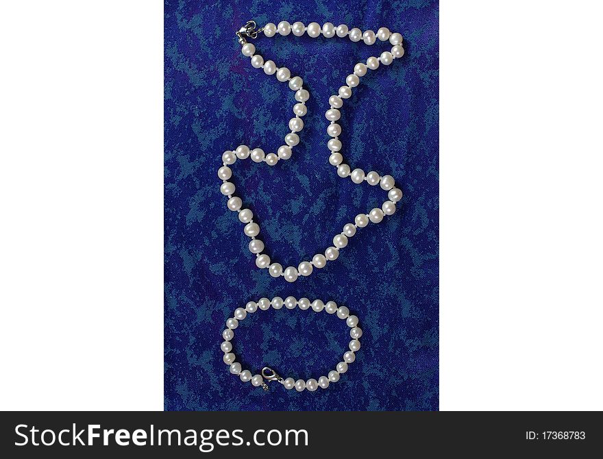 Pearl beads and a bracelet on the blue cloth