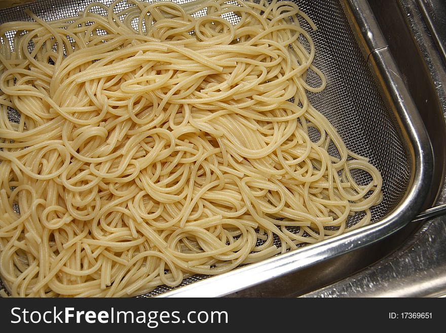 Draining spaghetti in a metal strainer. Draining spaghetti in a metal strainer