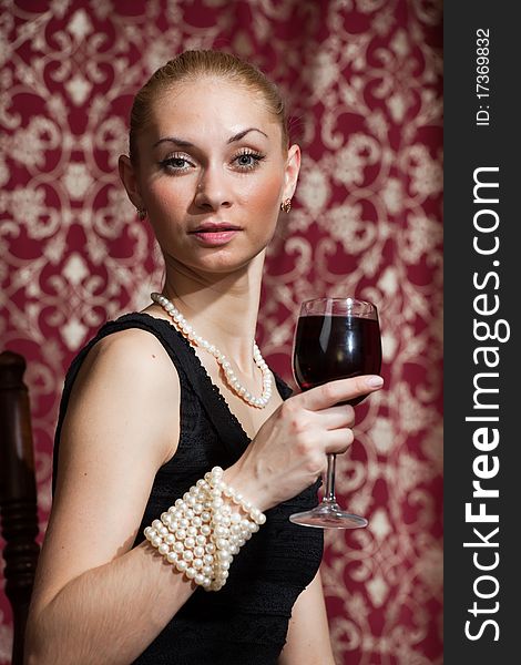 Studio portrait of a beautiful young blonde woman holding a glass of red wine. Studio portrait of a beautiful young blonde woman holding a glass of red wine