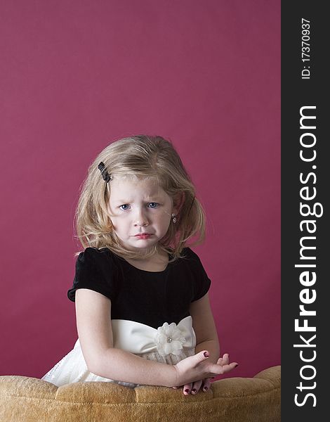 Very sad little girl standing behind couch. Very sad little girl standing behind couch