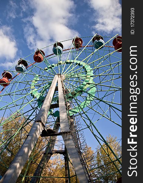Ferris wheel in an amusement park. Autumn. Against the blue sky.