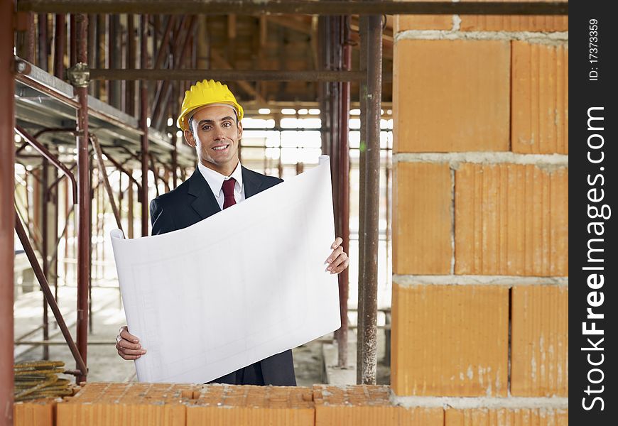 Caucasian male architect holding blueprints and looking at camera. Horizontal shape, waist up, front view, copy space. Caucasian male architect holding blueprints and looking at camera. Horizontal shape, waist up, front view, copy space