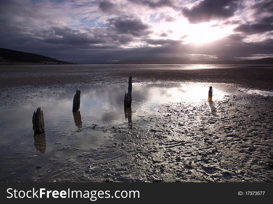 Peaceful sunset on beach in Lauderdale, with the remains of an ancient fence, Tasmania. Peaceful sunset on beach in Lauderdale, with the remains of an ancient fence, Tasmania.