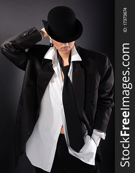 Young fashion model in hat, big man shirt and coat against black. Young fashion model in hat, big man shirt and coat against black