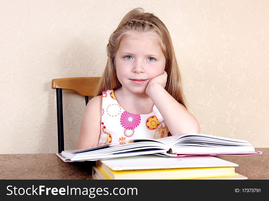 Little girl reading book against yellow wall at home