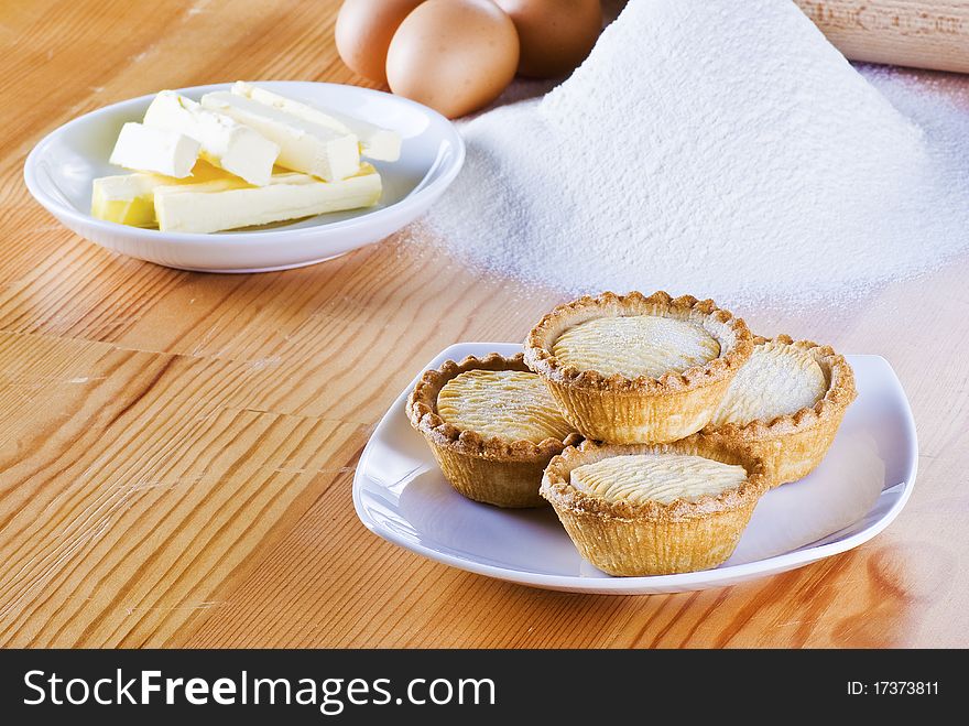 Freshly made apple pies on the table with flour eggs and butter. Freshly made apple pies on the table with flour eggs and butter