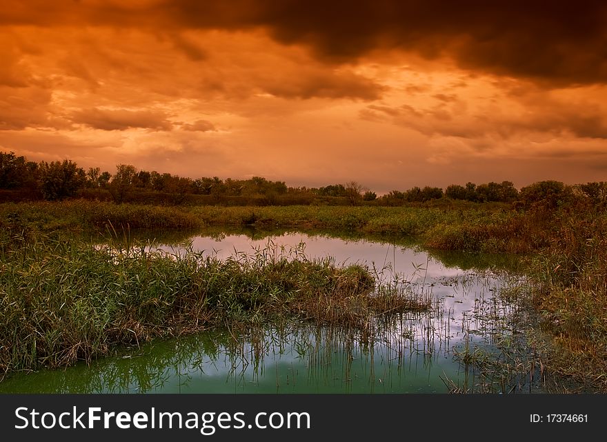 Landscape with old pond and dramatic sky