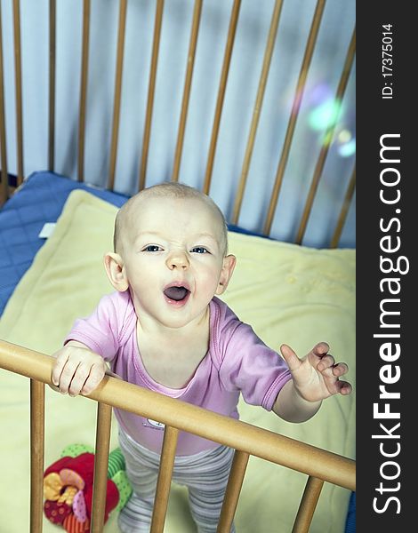 Little baby holds on to the baby bed and is happy about soap bubbles. Little baby holds on to the baby bed and is happy about soap bubbles