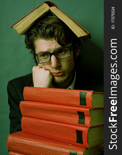 Portret of sad young man with a stack of red books