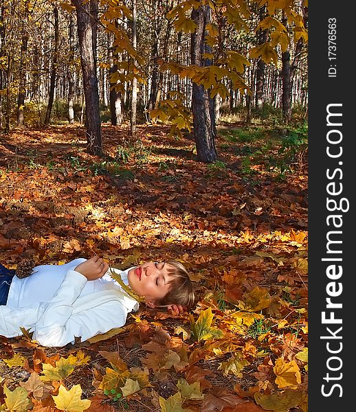 Beautiful blonde with leaf in the autumn forest