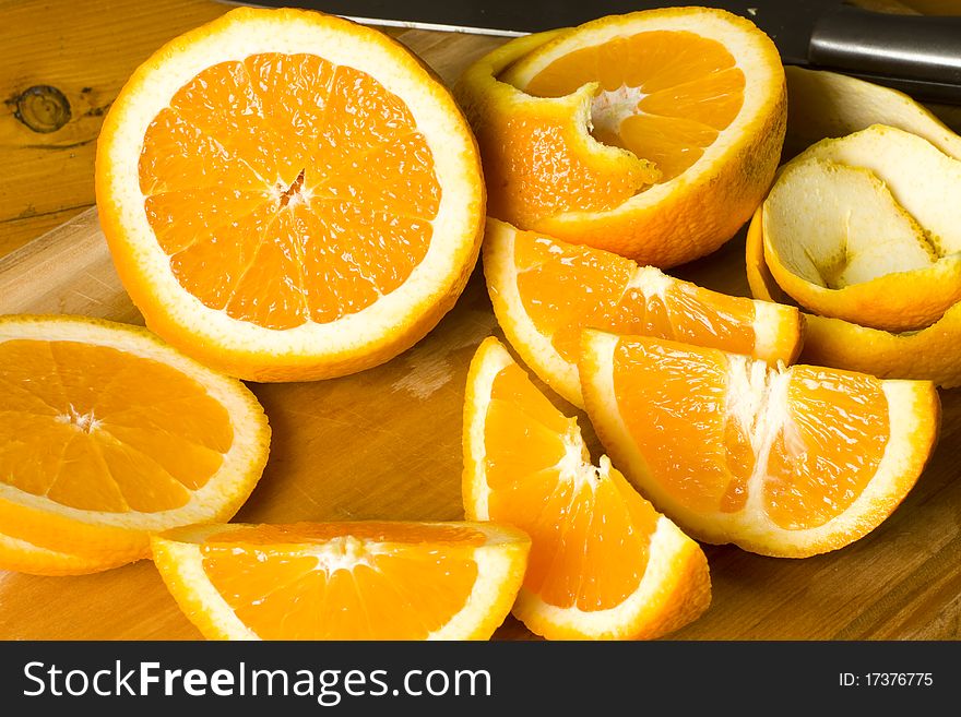 Fresh organic orange pieces with peel on a wooden cutting board. Fresh organic orange pieces with peel on a wooden cutting board