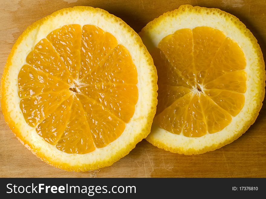 Fresh organic orange wheel pieces with peel on a wooden cutting board. Fresh organic orange wheel pieces with peel on a wooden cutting board