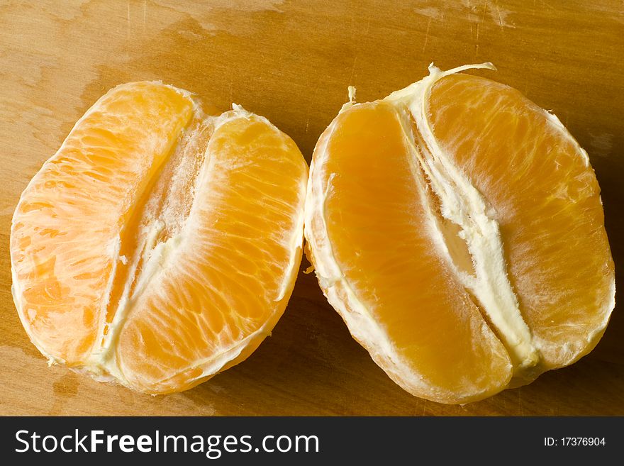 Peeled halves of fresh organic orange on a wooden cutting board. Peeled halves of fresh organic orange on a wooden cutting board